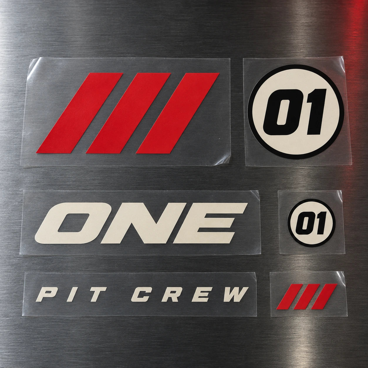 Separate 01, ONE, PIT CREW, and red speed-mark transfers on clear carrier film.